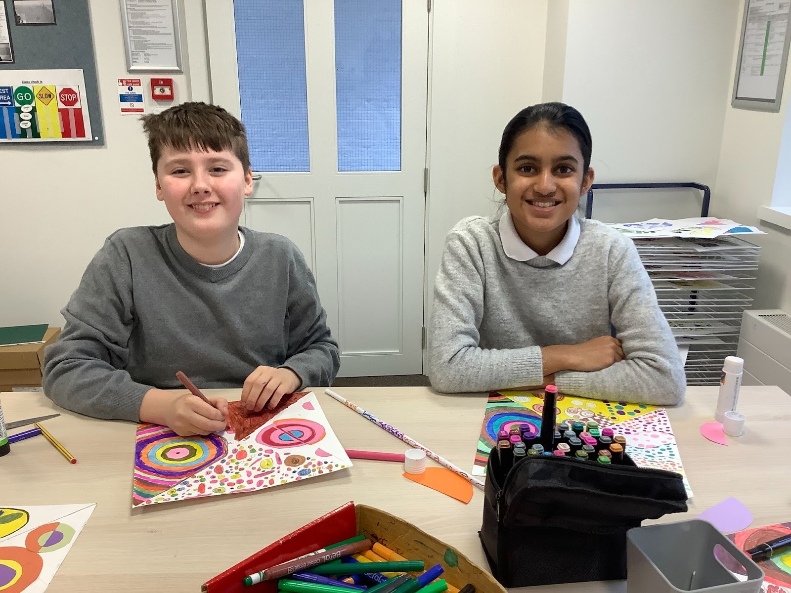 Two students smiling with their bright windmill art