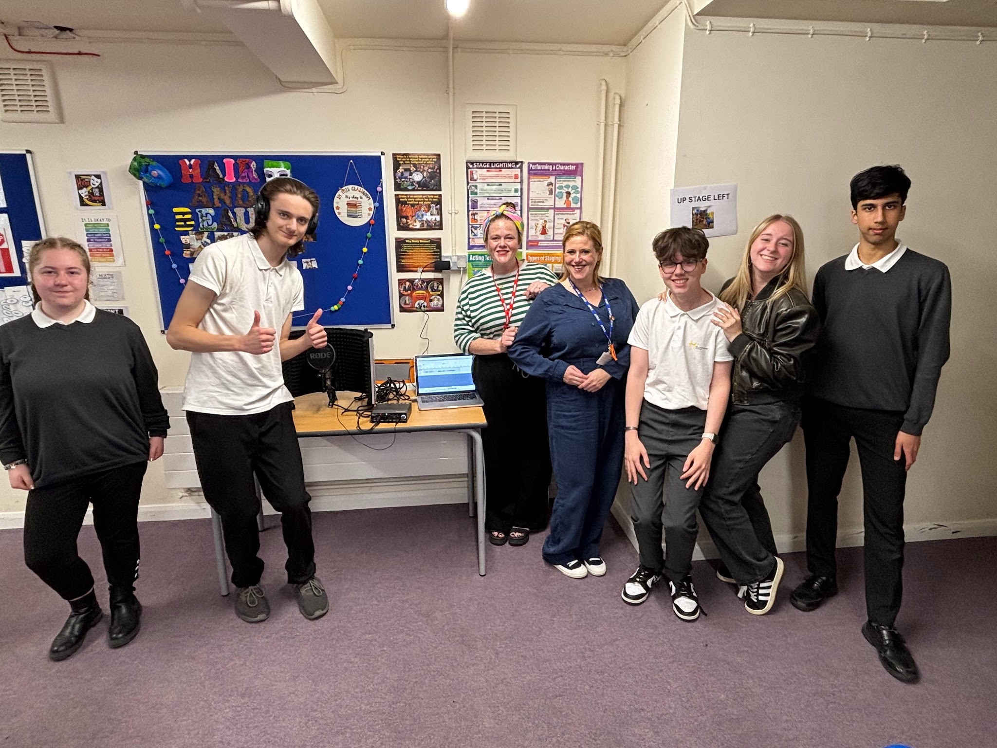 Students smiling with their drama teacher and visiting actor