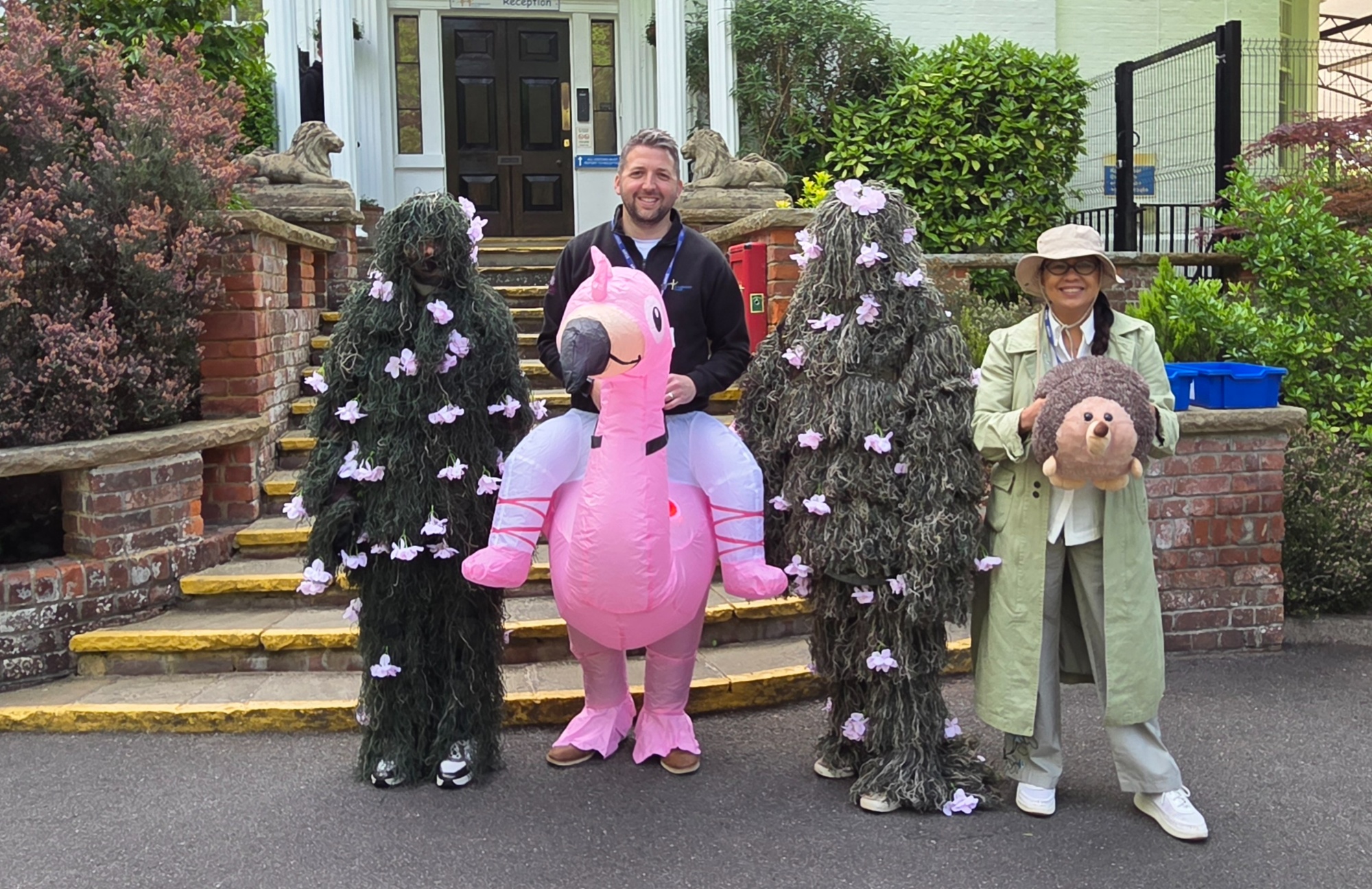 Staff dressed up in front of the school - including one riding an inflatable flamingo!