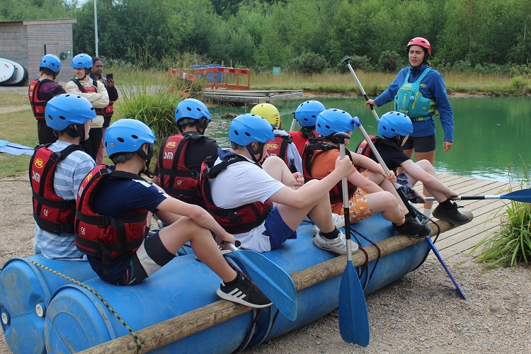 Students witting on their completed raft about to set sail