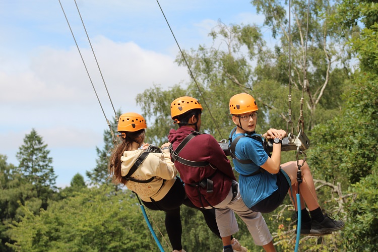 Two students and a member of staff on the big swing