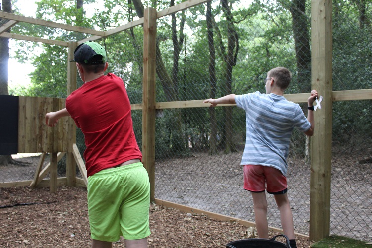Two boys practicing their axe throwing