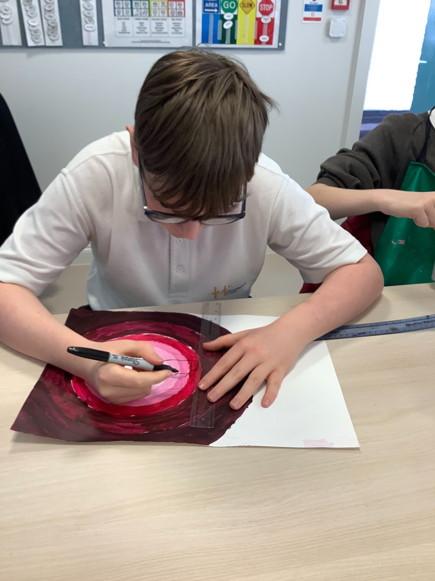 Student painting a silhouette on a red background