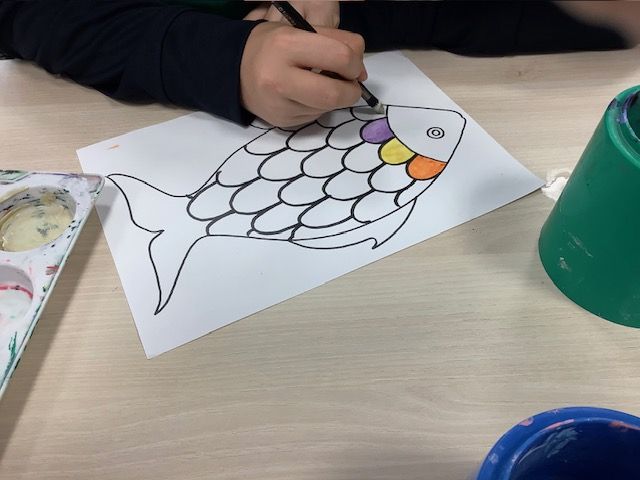 Student colouring in fish scales on a picture