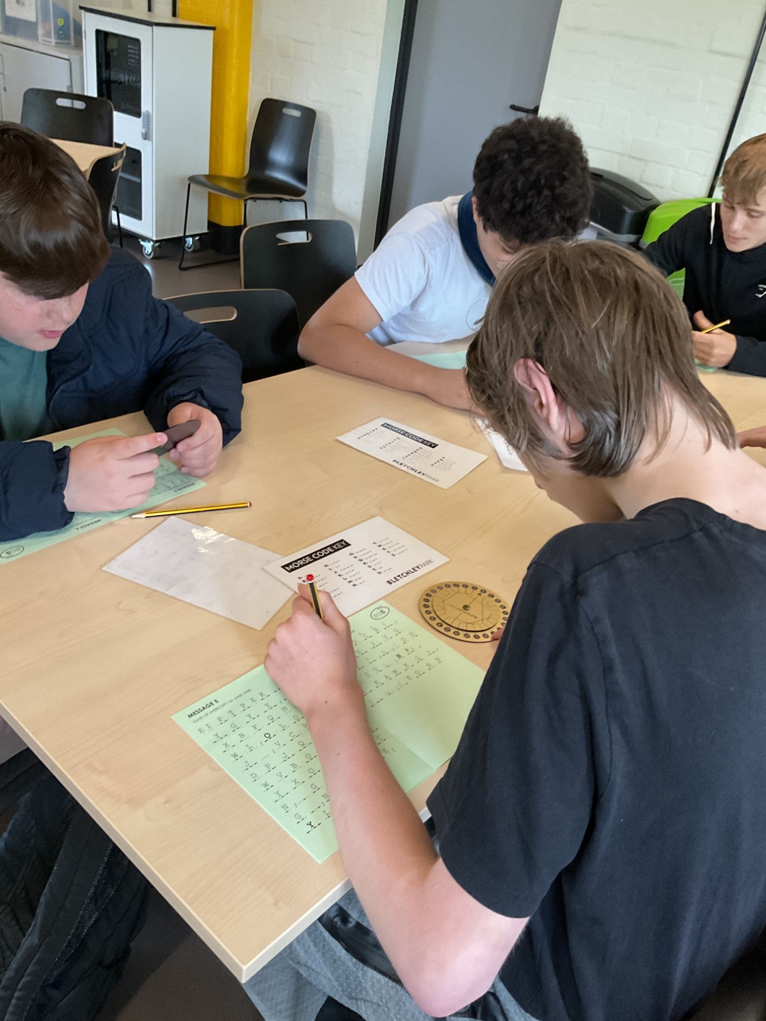 Three students usinf a cardboard wheel to solve codes