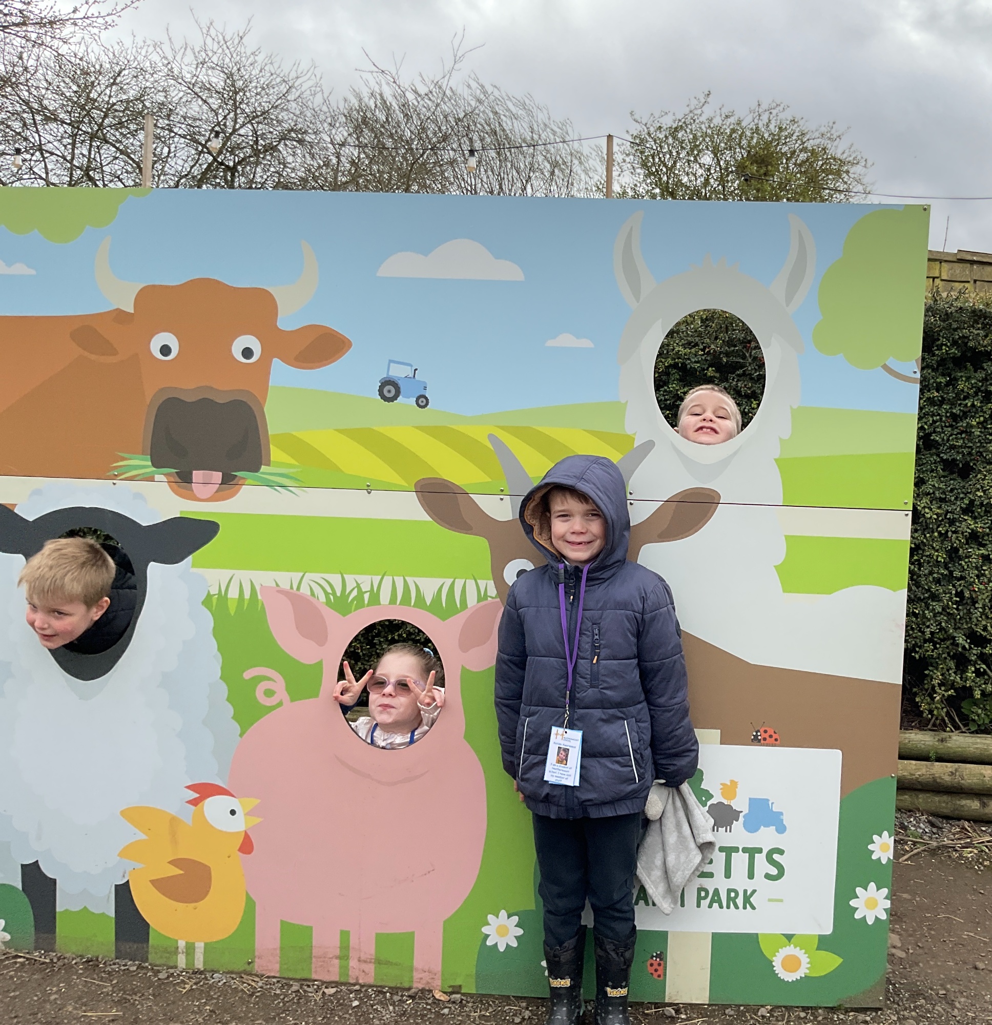 Students putting their heads through the pictures of animals on the farm sign