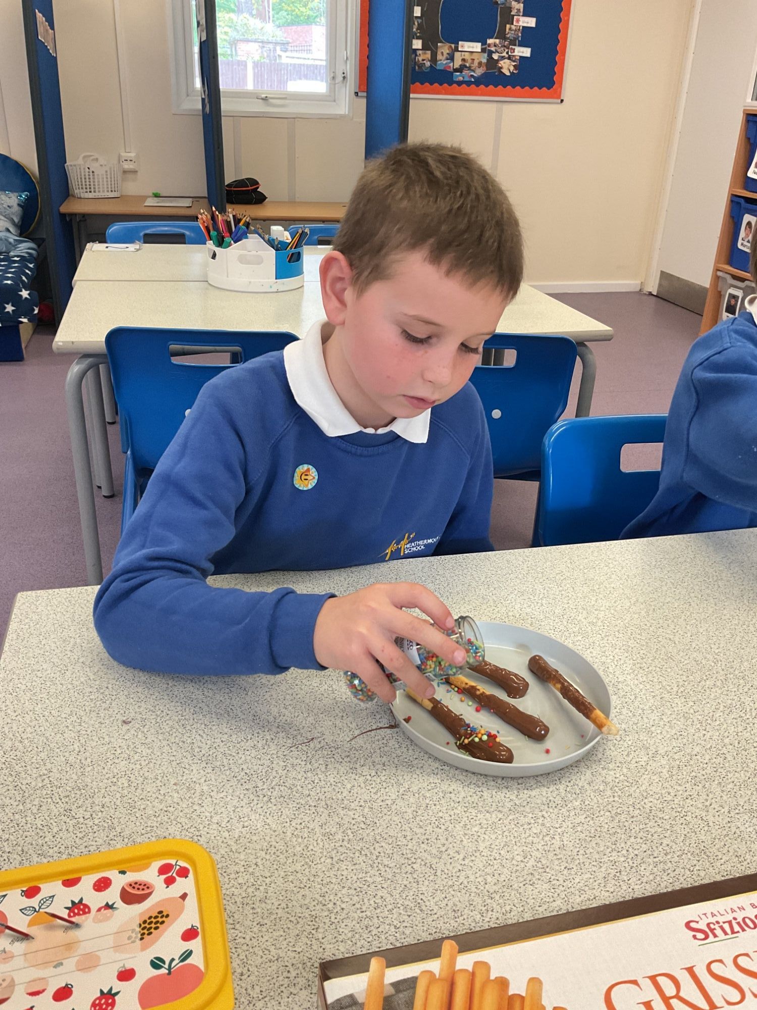 Boy from Apple Class pouring sprinkles on his sparklers