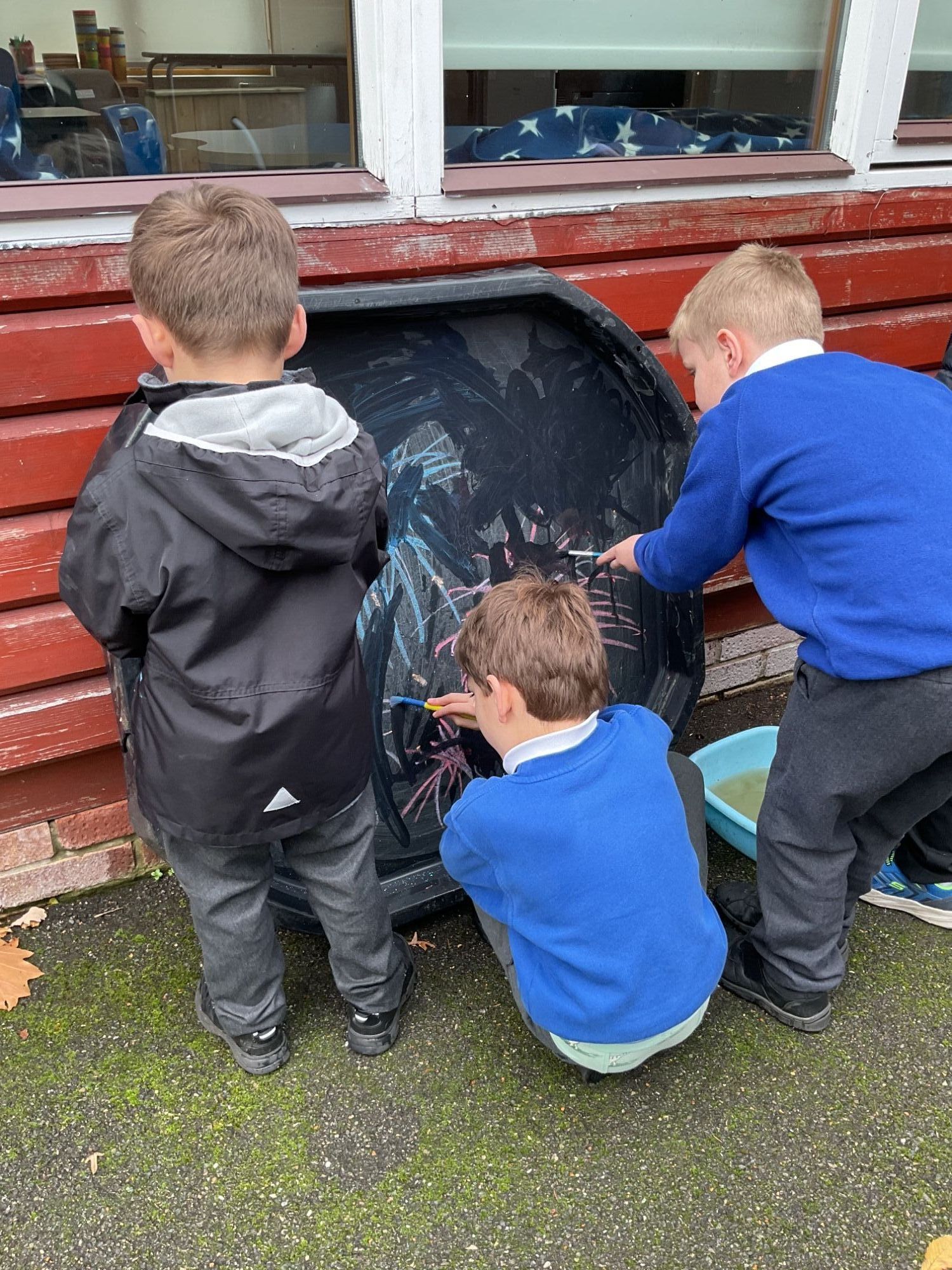 Three boys drawing fireworks with chalk