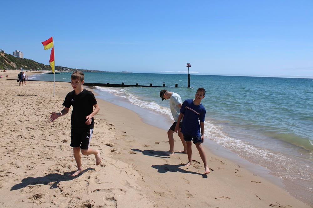 Three students playing football on the beach
