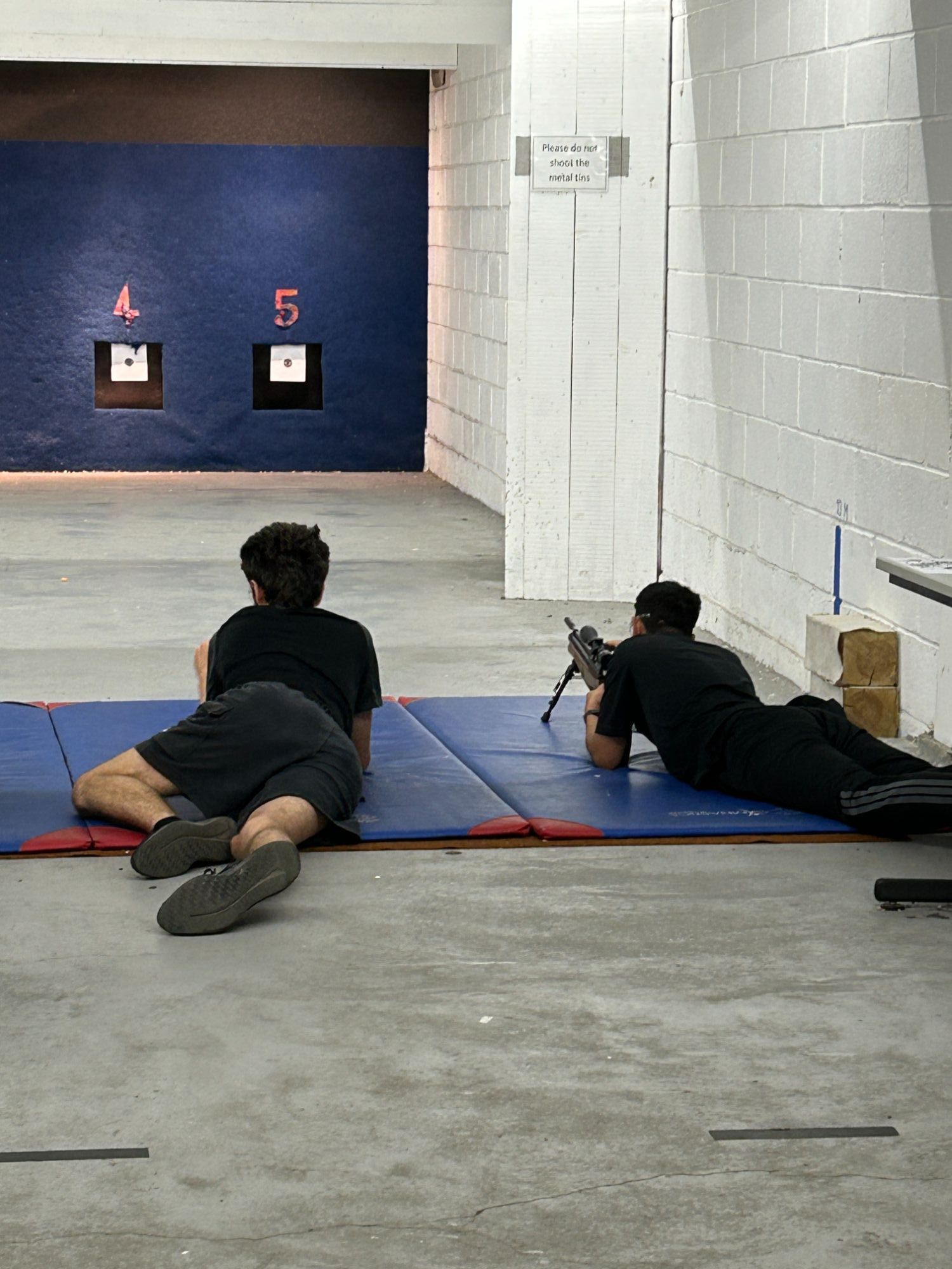 Two students lying down firing rifles at the range