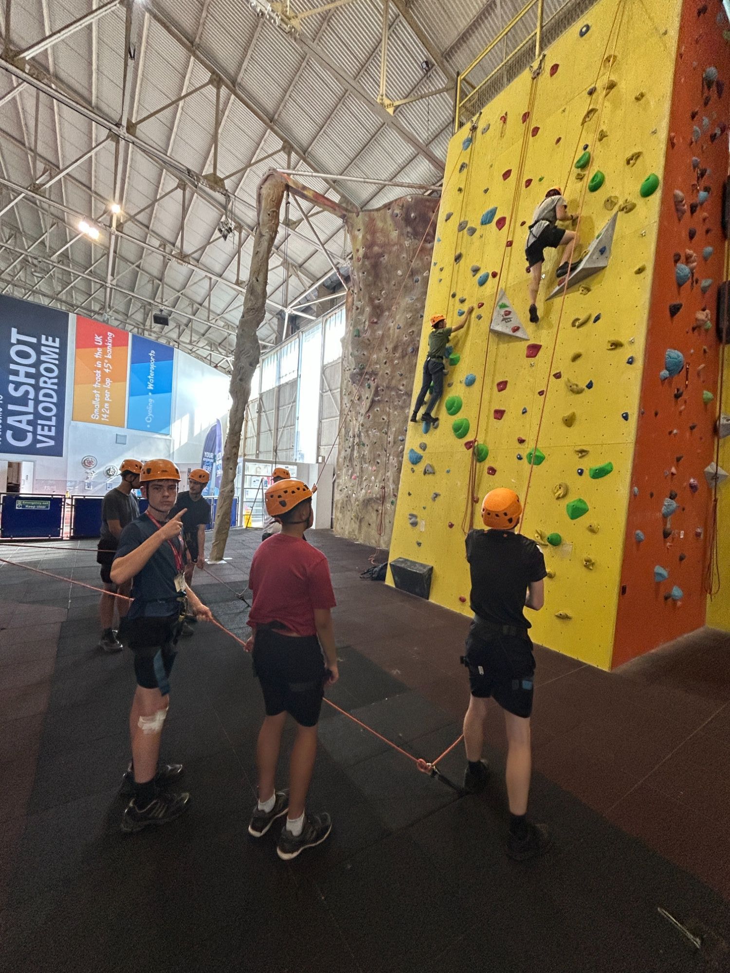 Students climbing up a bright yellow climbing wall
