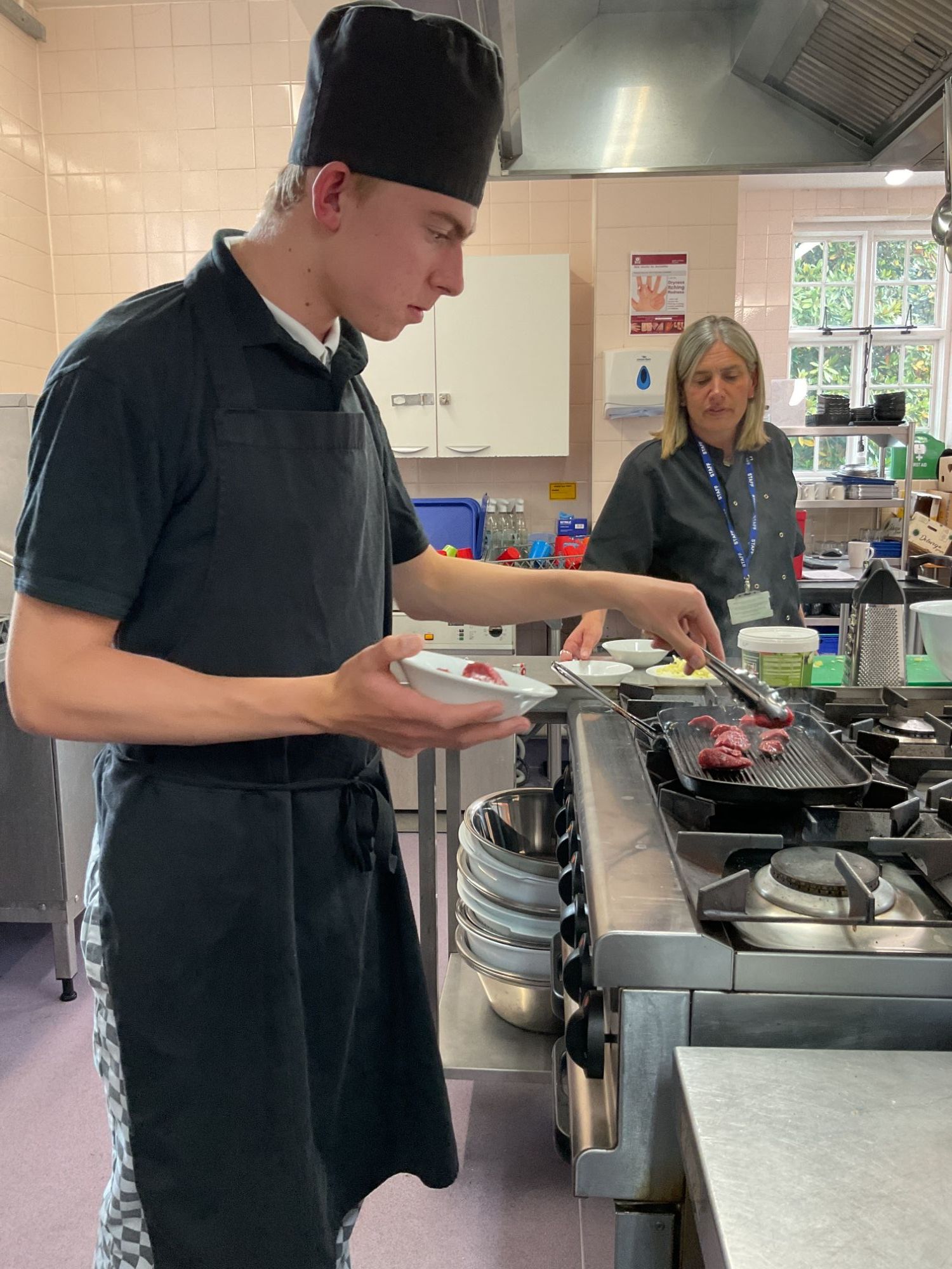 Student placing his beef on the griddle to cook