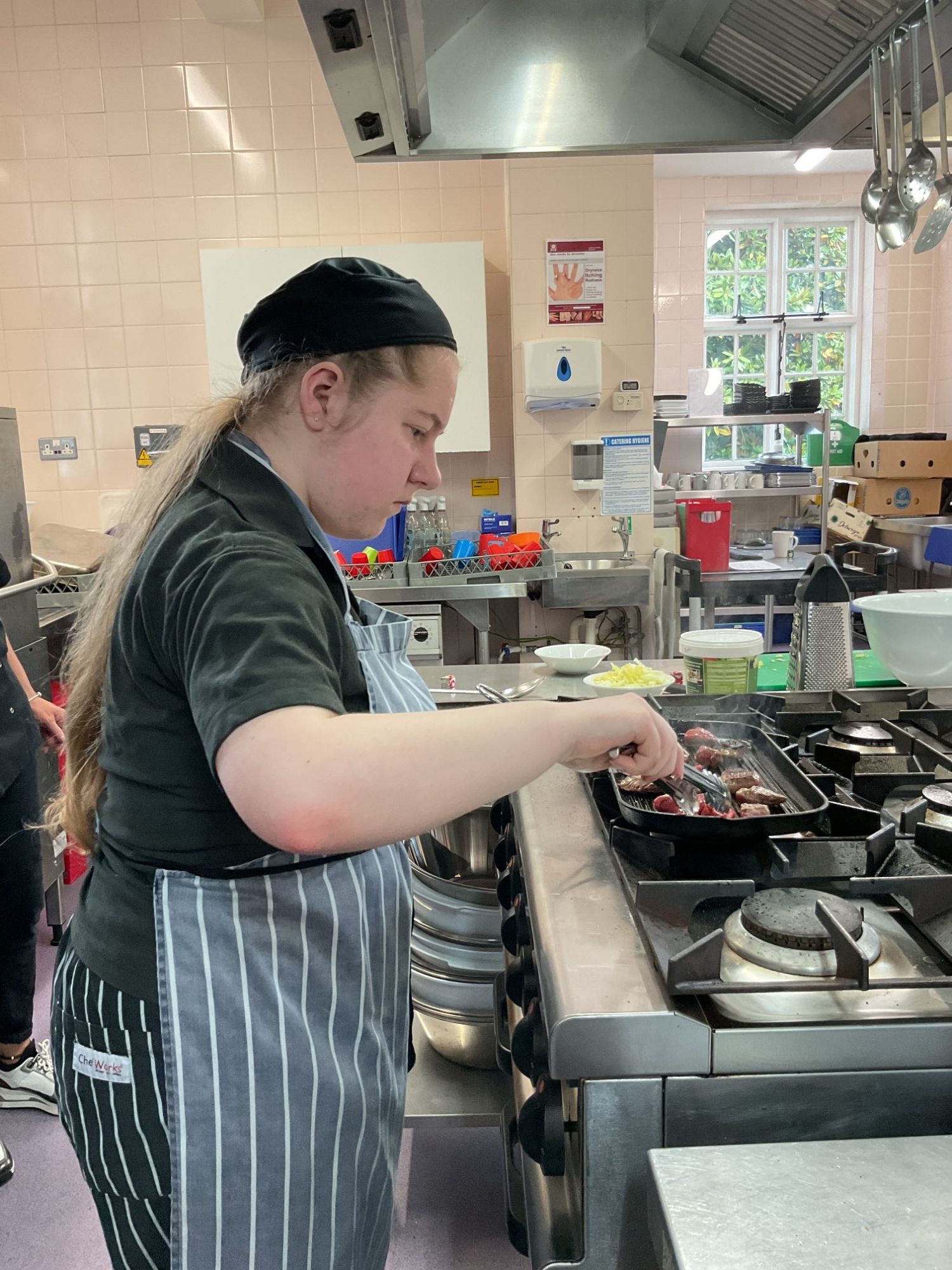 Female student carefully cooking her beef on the griddle