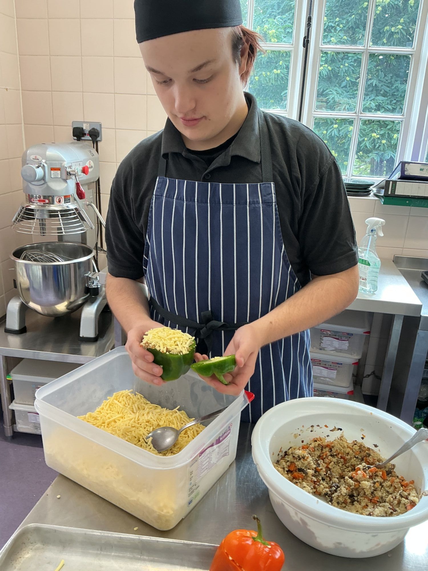 Student adding cheese to the top of his stuffed pepper