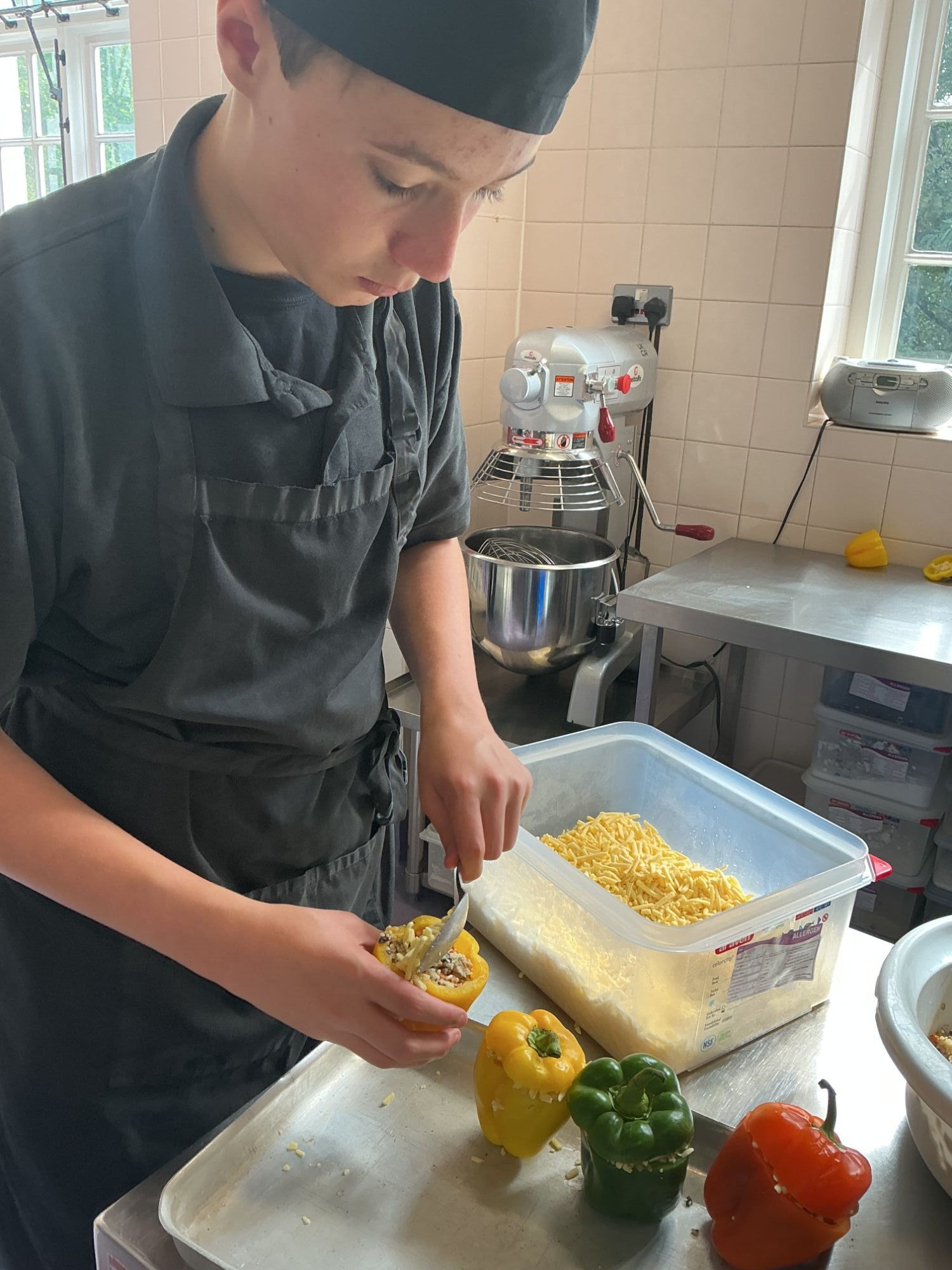 3 Peppers Student adding his third stuffed pepper to a baking tray