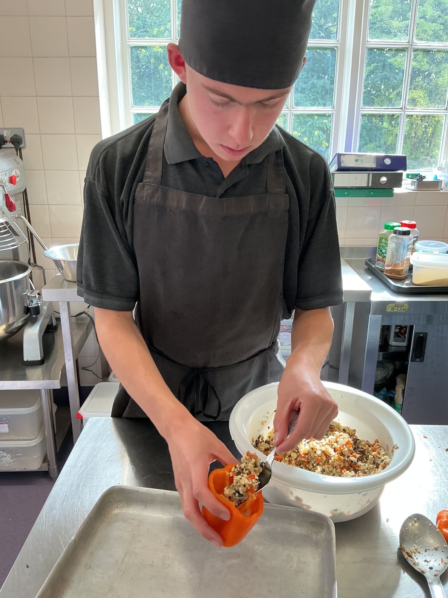 Student adding his cous cous mixture to a red pepper
