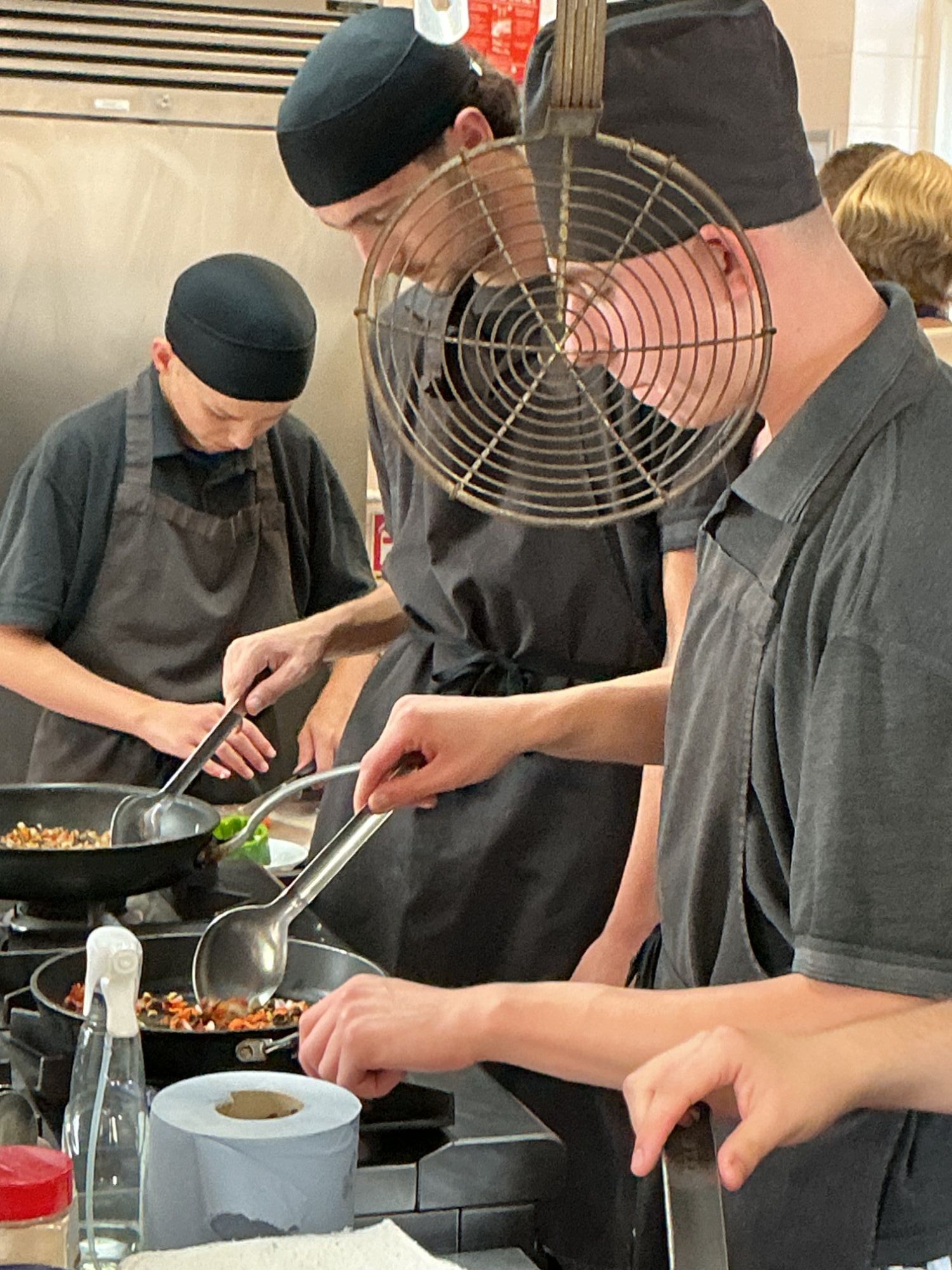 Group of students frying their vegetables in the school kitchen.