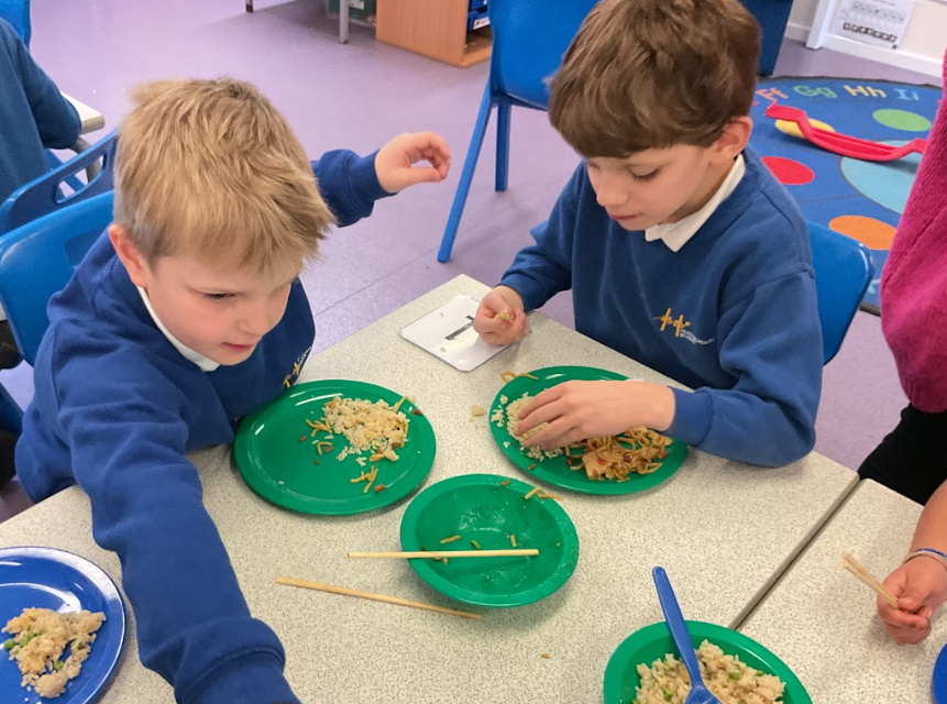 Two boys trying rice and noodles