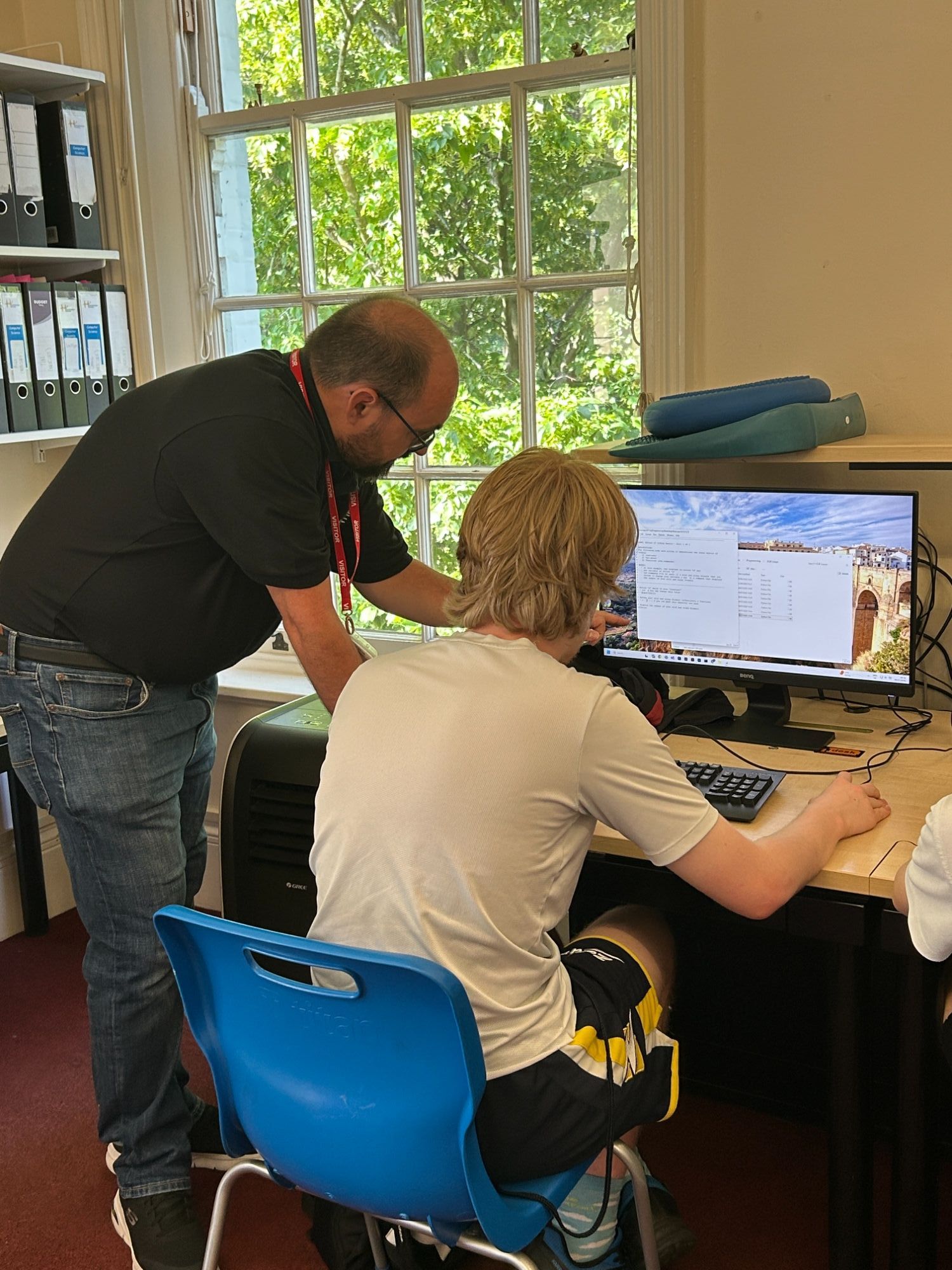 Visitor helping a student with coding