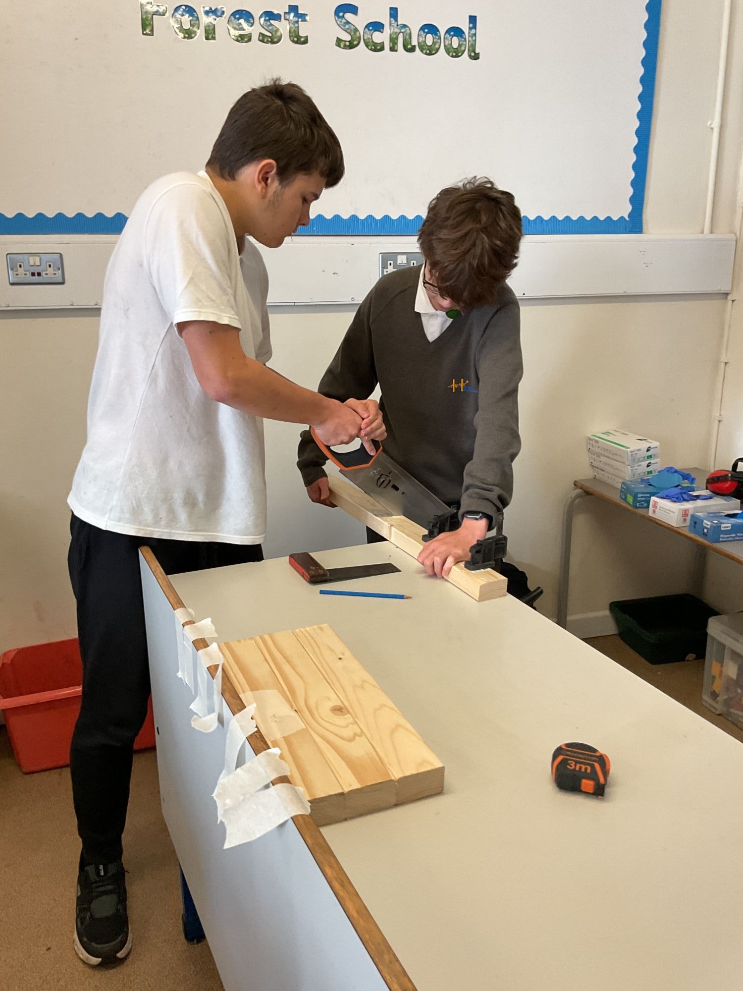 Two students working together to saw wood