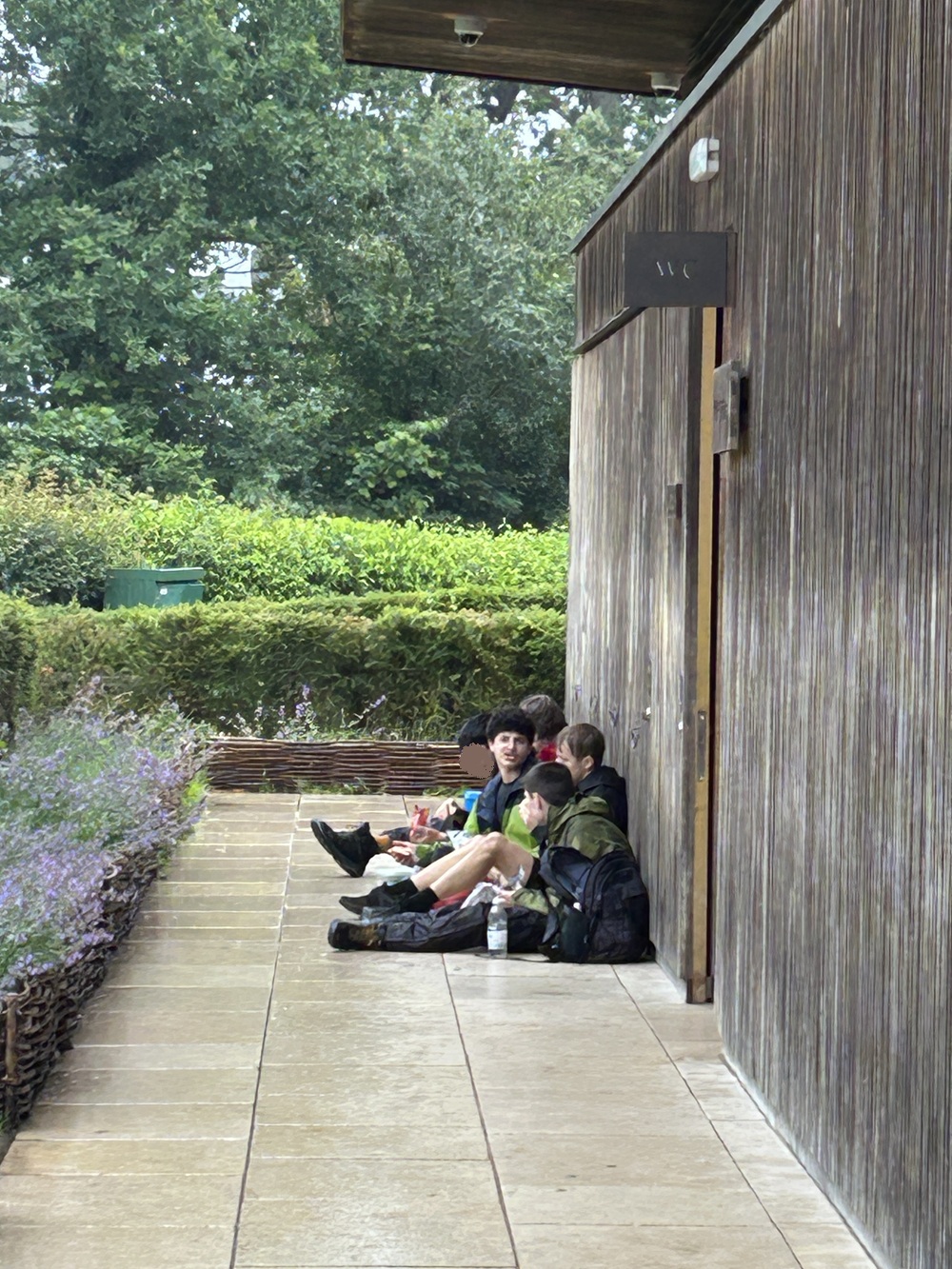 Group of students sitting down to rest leaning against a building