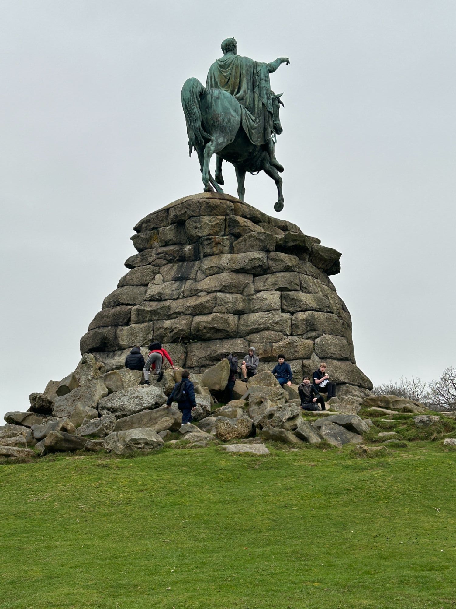 Students climbing up the foot of a big monument