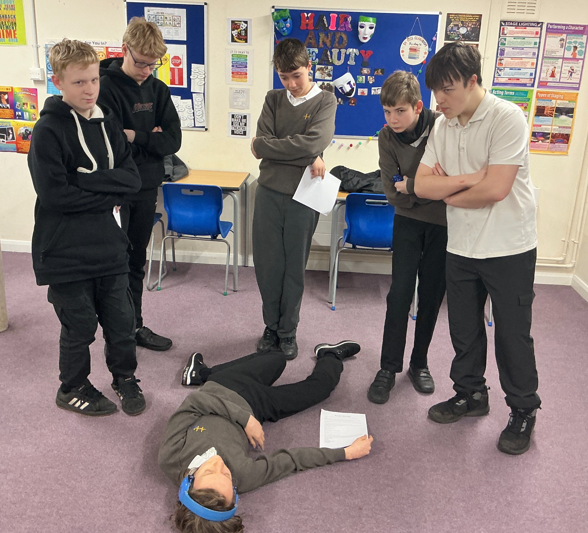 Students stood around a boy lying on the floor