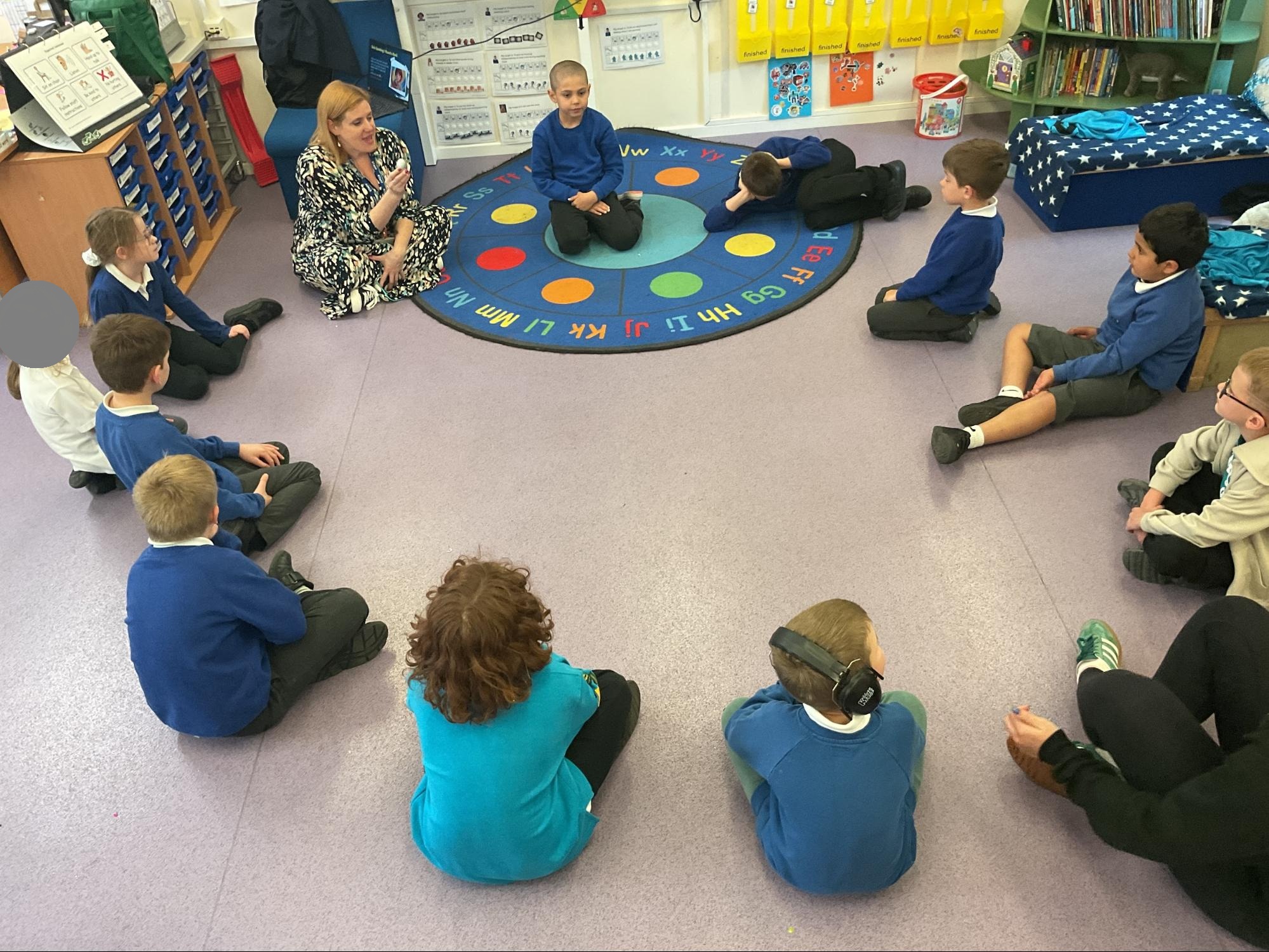 Foundation class sitting in a circle on the floor with the drama teacher