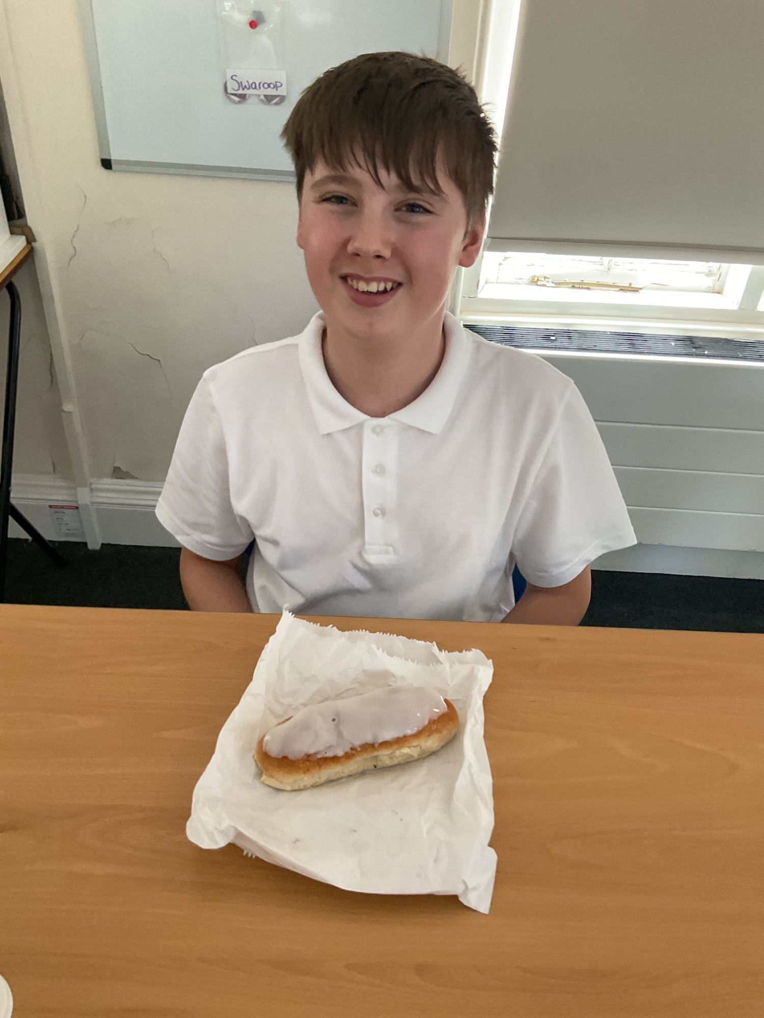 Student smiling with his iced bun in front of him