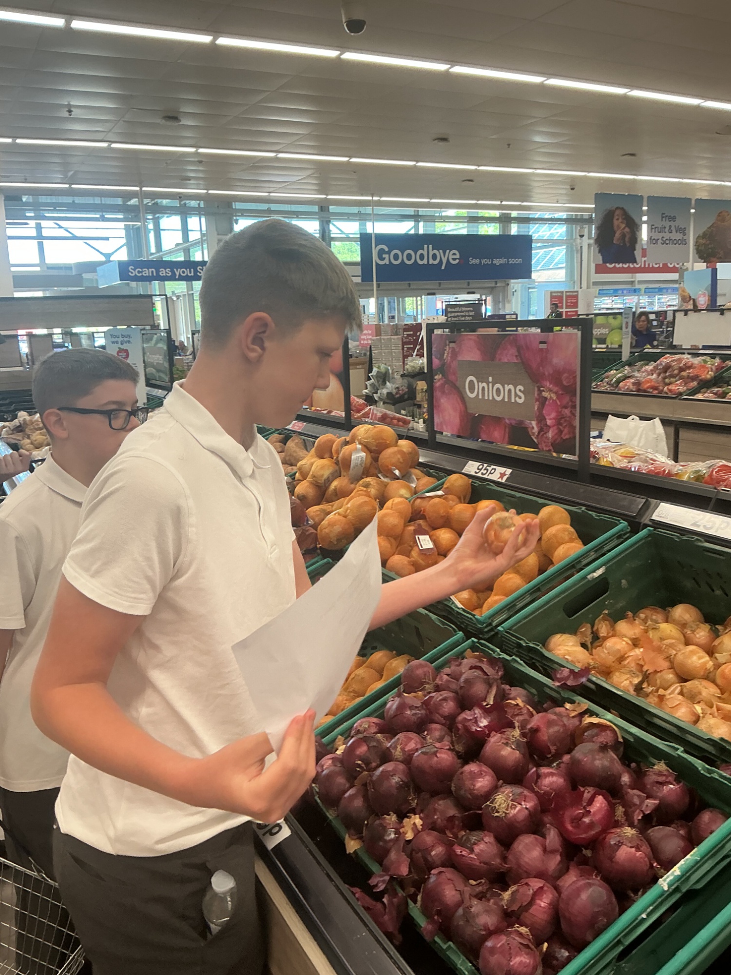 Two children choose onions for their recipe