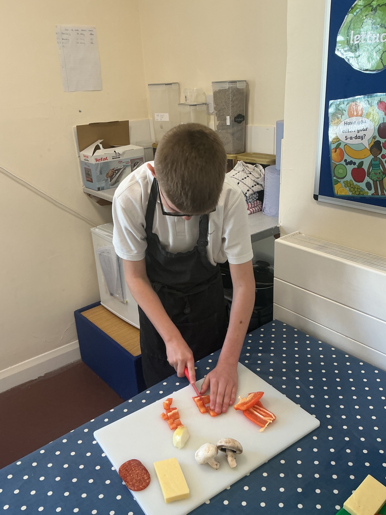 Student cutting up vegetables to prepare for his recipe