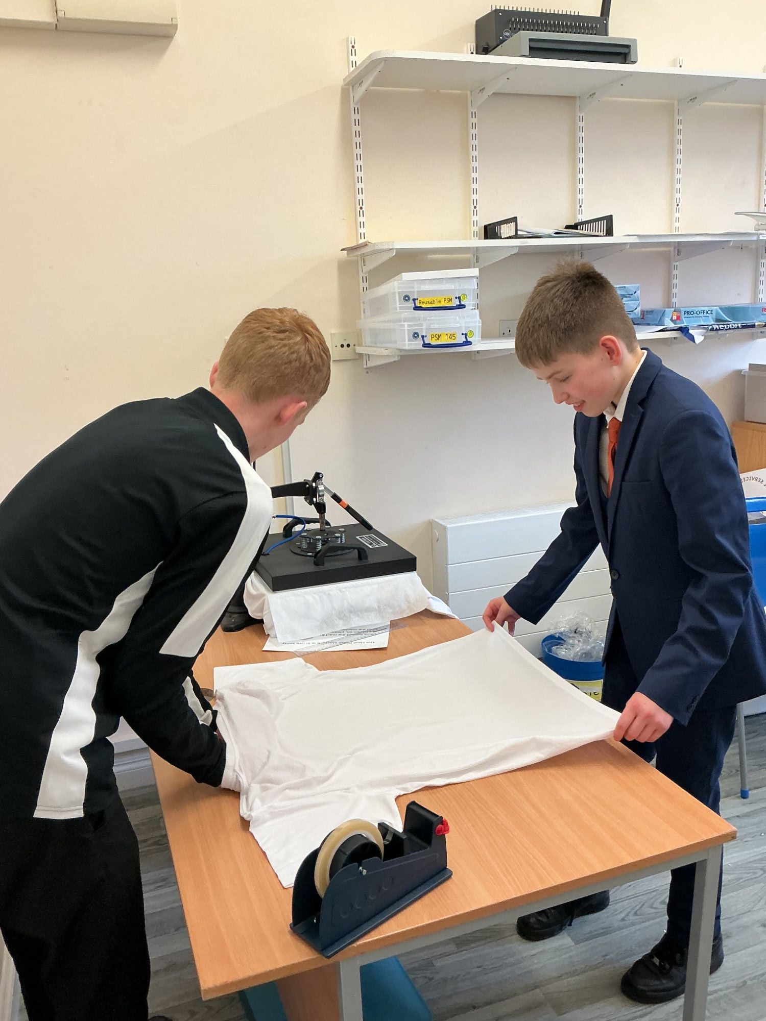 Two students carefully folding a t-shirt