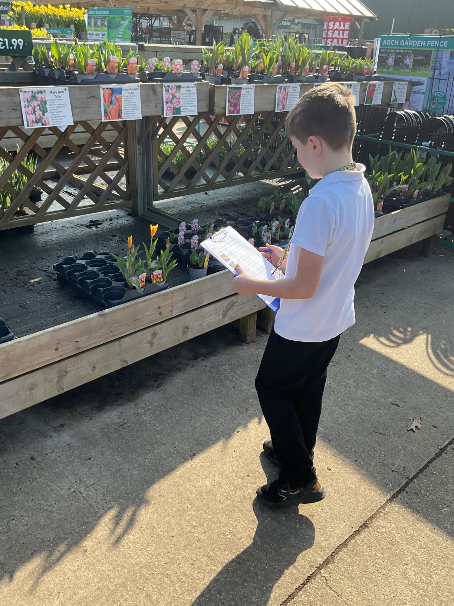Student with clipboard looking at plants at the garden centre