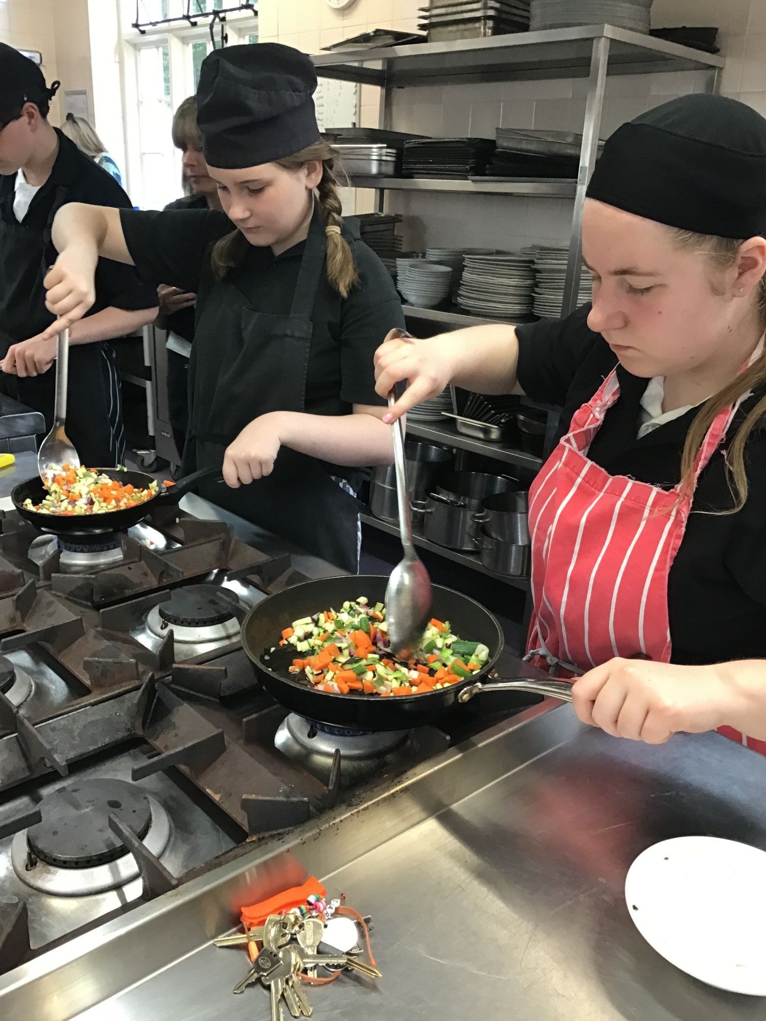 Two students frying vegetables Two students frying vegetables