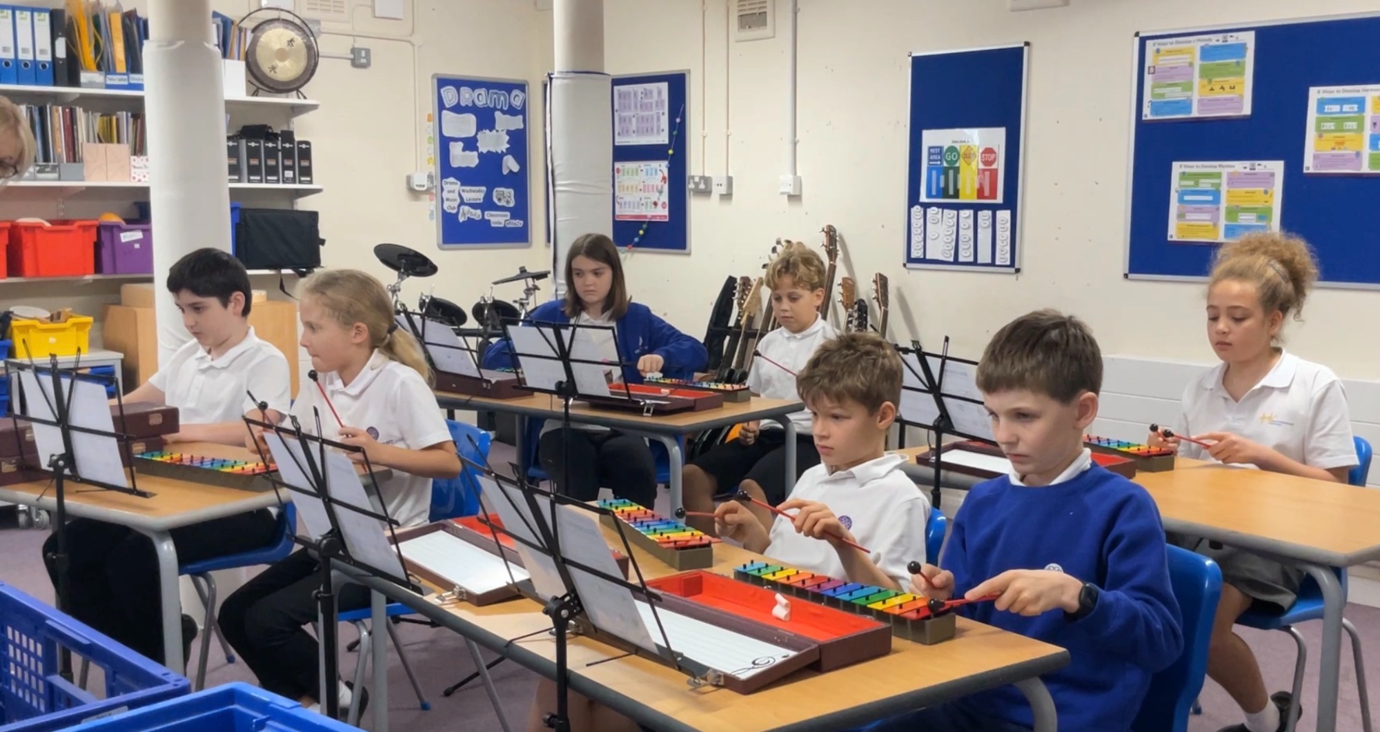 Students at desks playing a range of percussion instruments