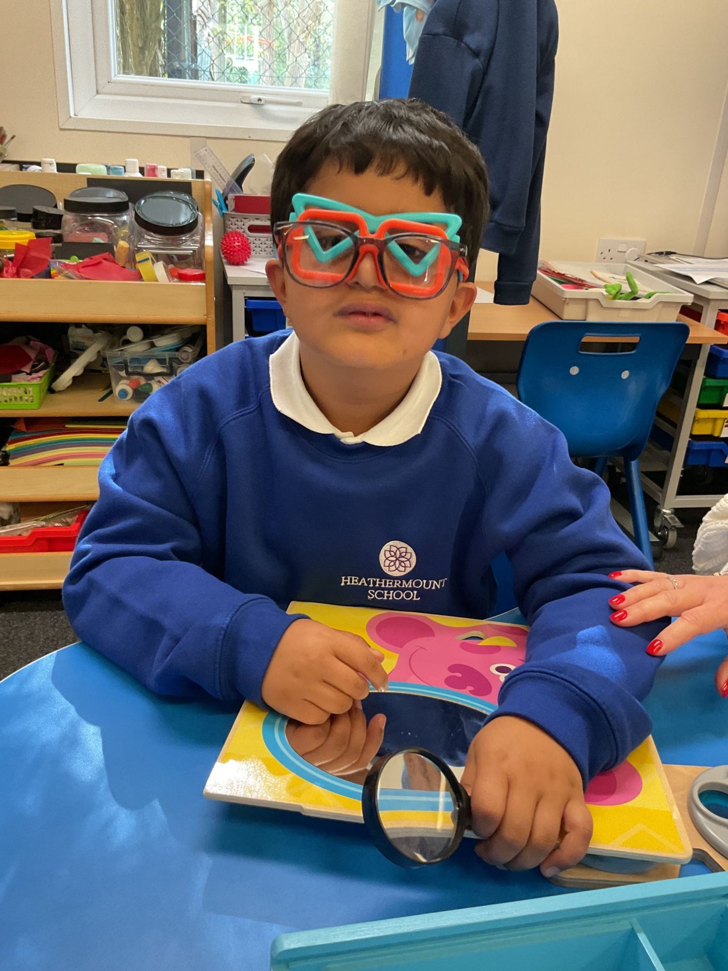 Student wearing lots of different colourful glasses the class has made