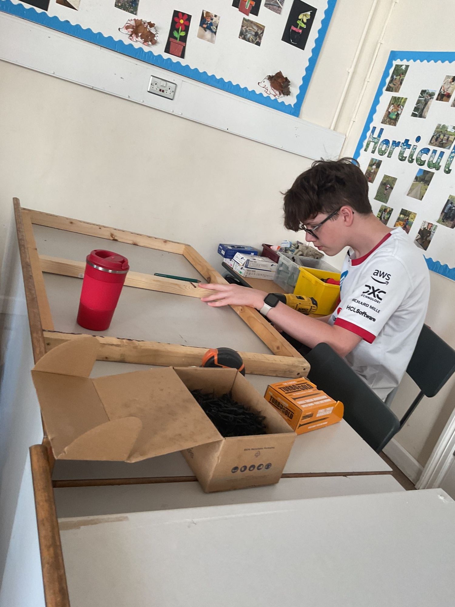 Boy attaching plasterboard to a wooden frame