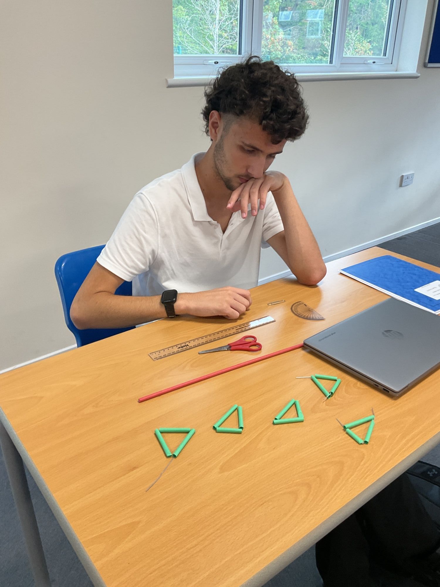 Student with traingles he has made on the desk in front of him