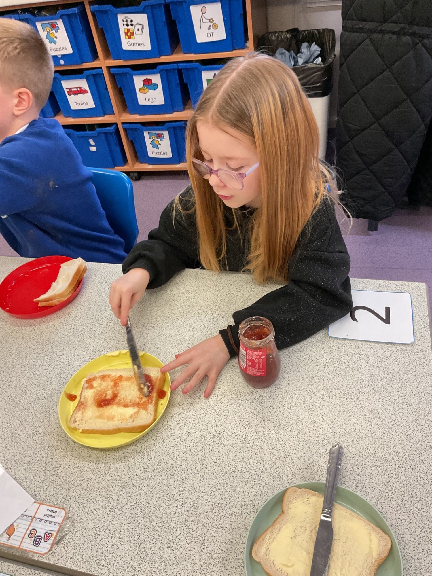 Girl carefully spreading jam on her sandwich