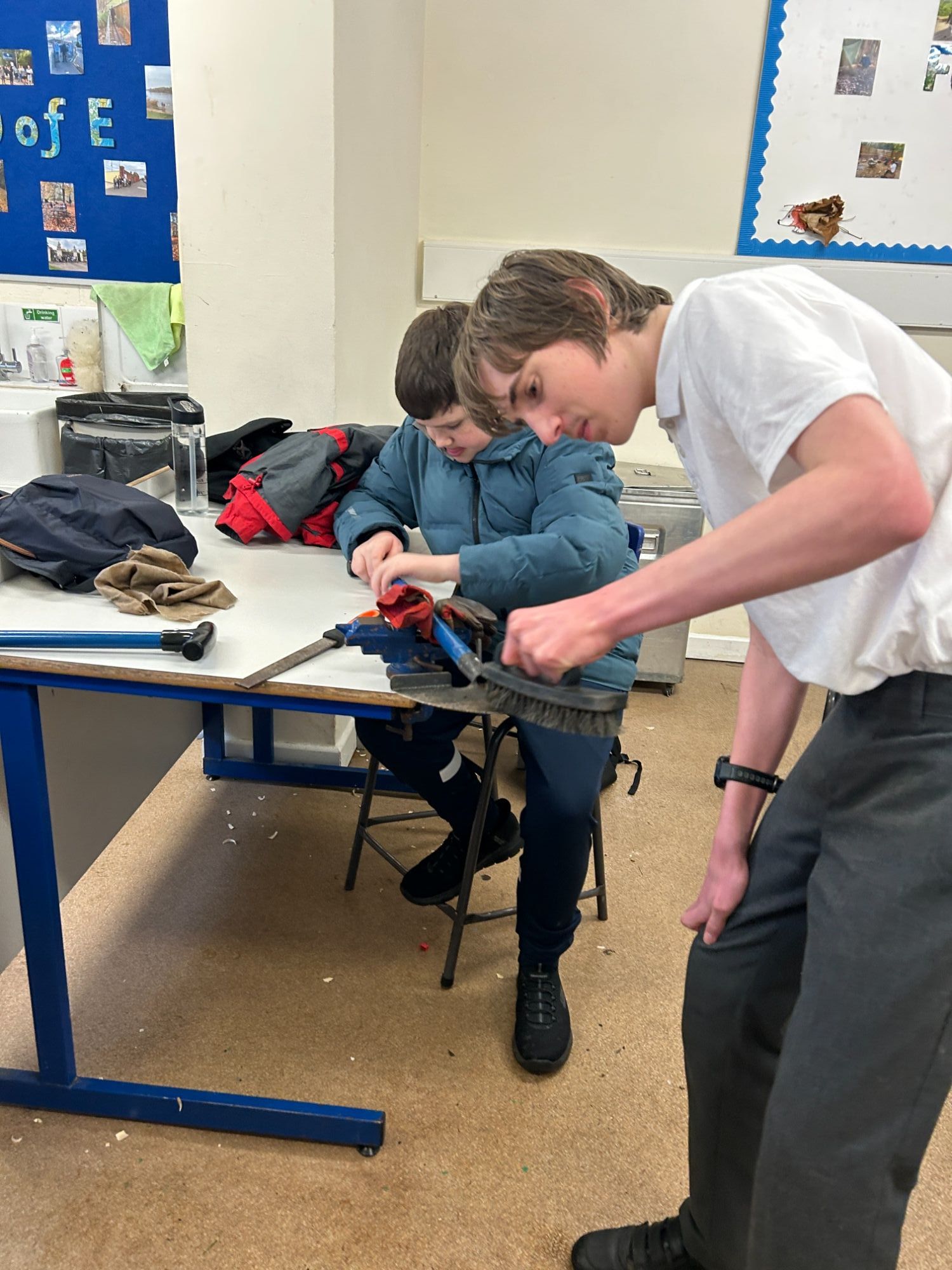 Two boys working together to sharpen a tool