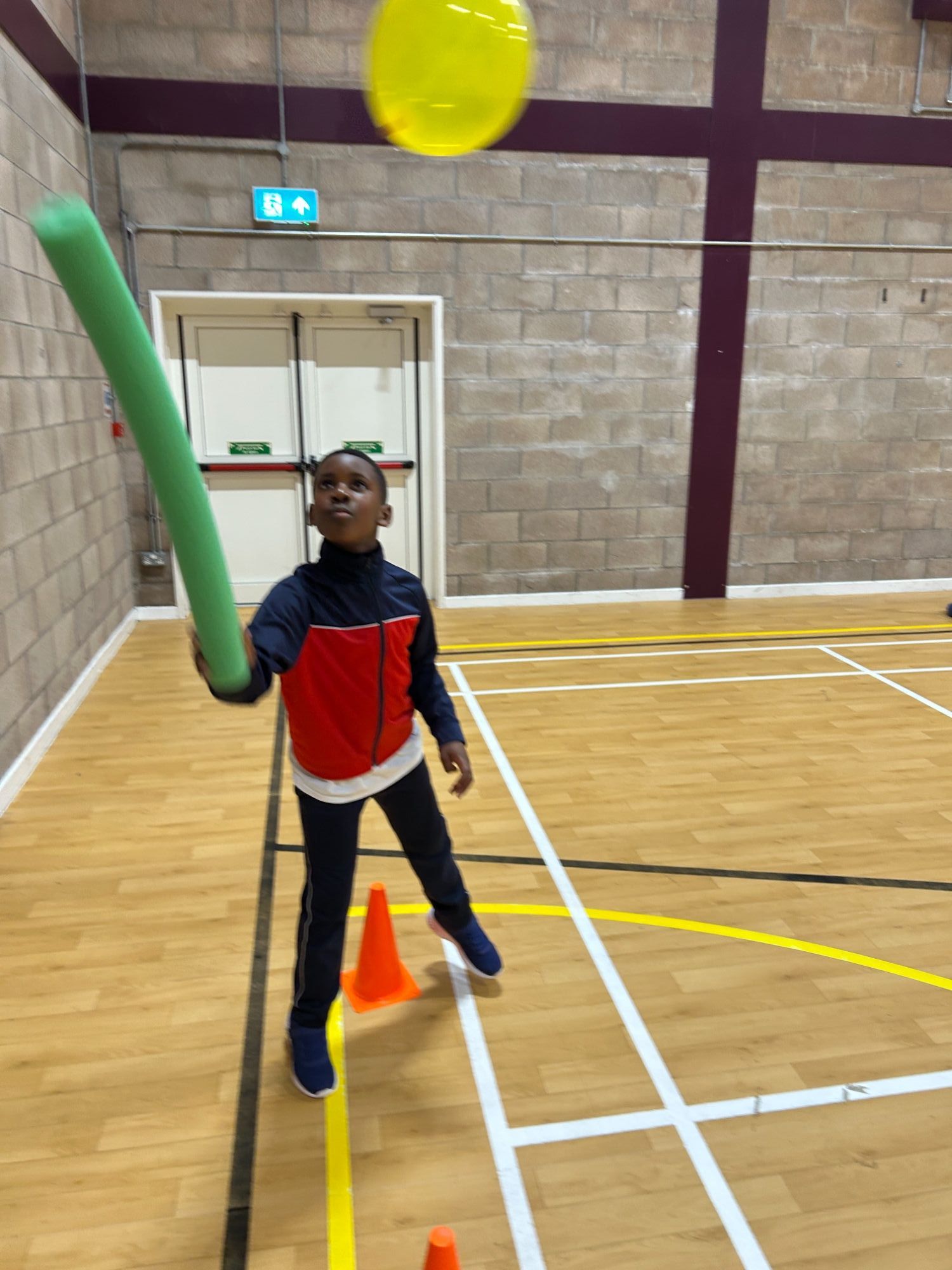 Boy keeping a balloon in the air with a foam stick