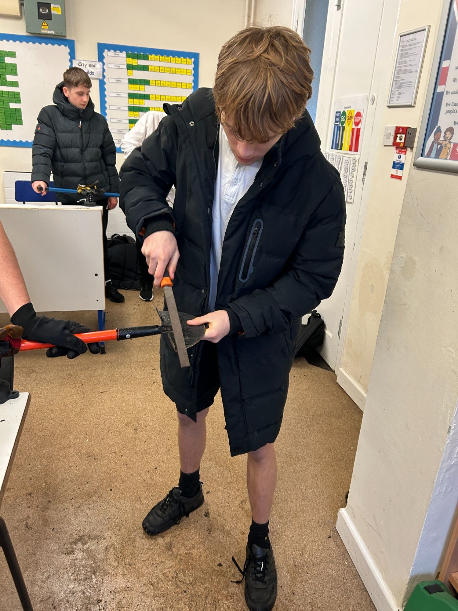 Boy sharpening a tool with a file