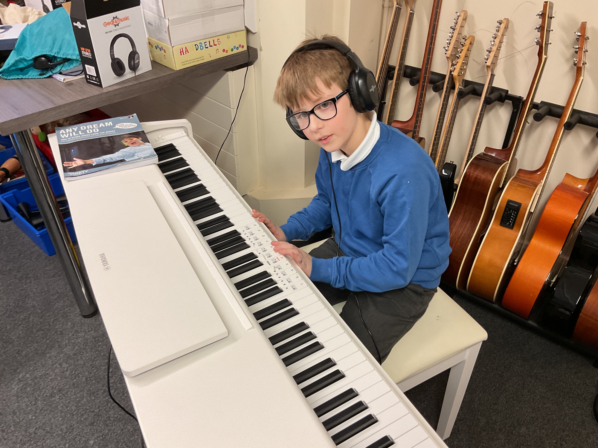 Boy in headphones playing on a white keyboard