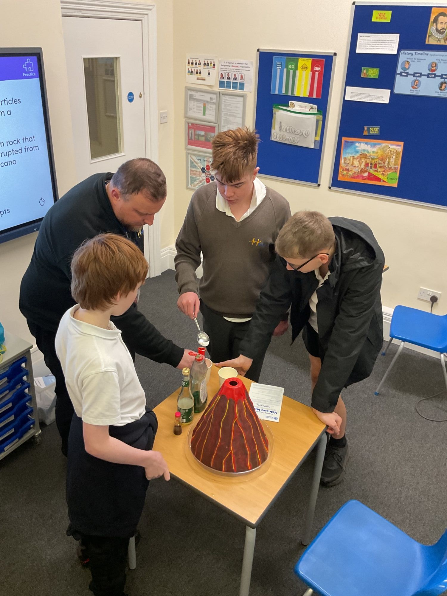Teacher helping students with their volcano exp[eriment