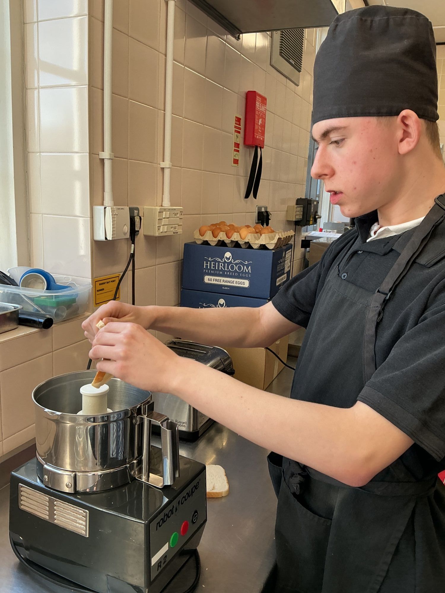 Student adding bread to a machine to make breadcrumbs