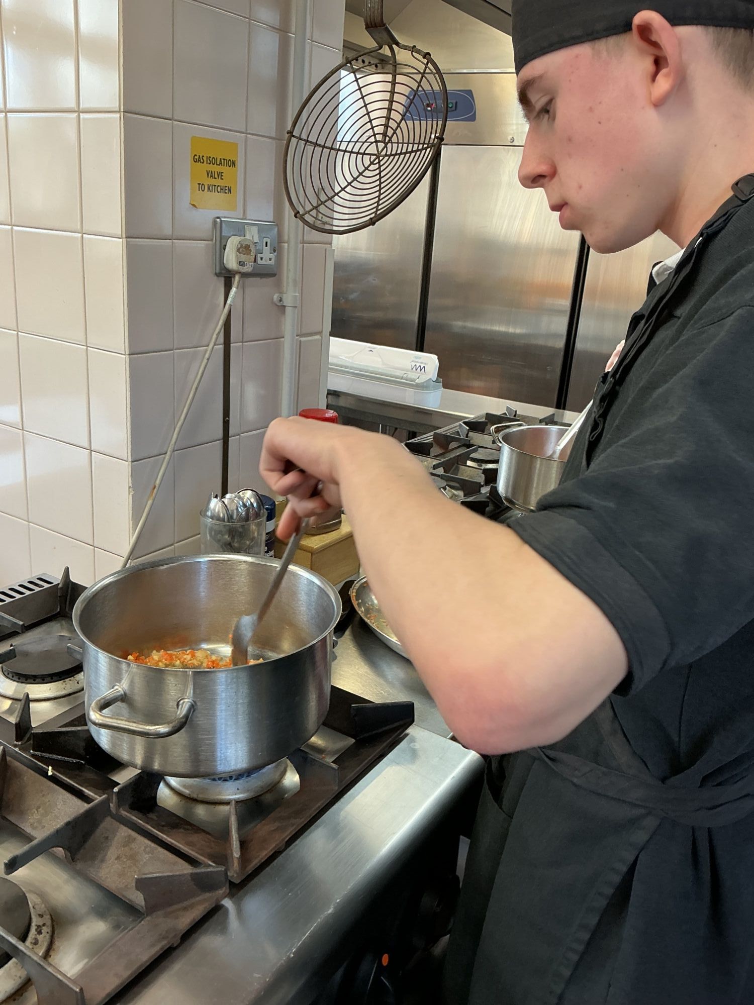 Student frying vegetables for their sauce
