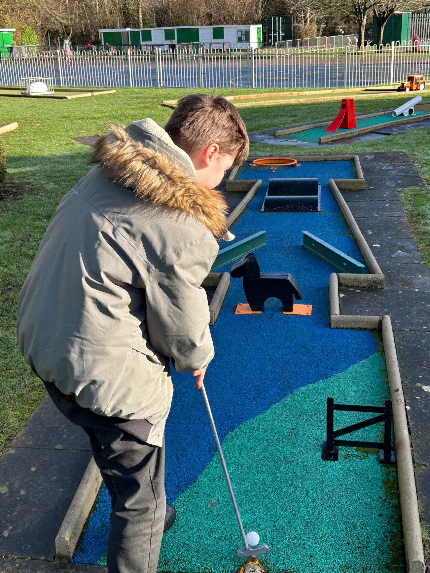 Boy about to hit his ball through many obstacles
