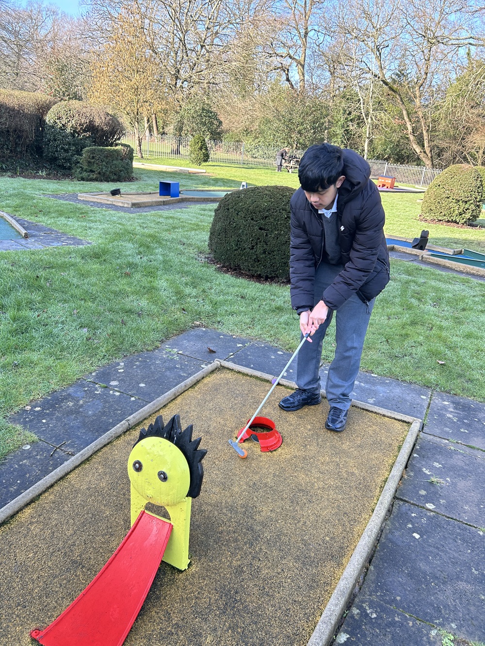 Boy at the end of a golf hole ready to put