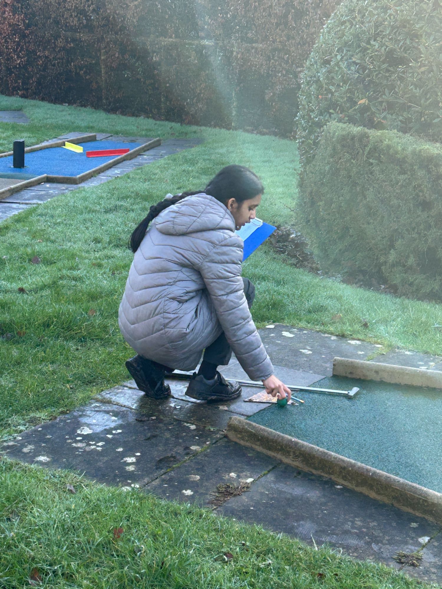 Girl with clip board placing her ball at the start of a hole