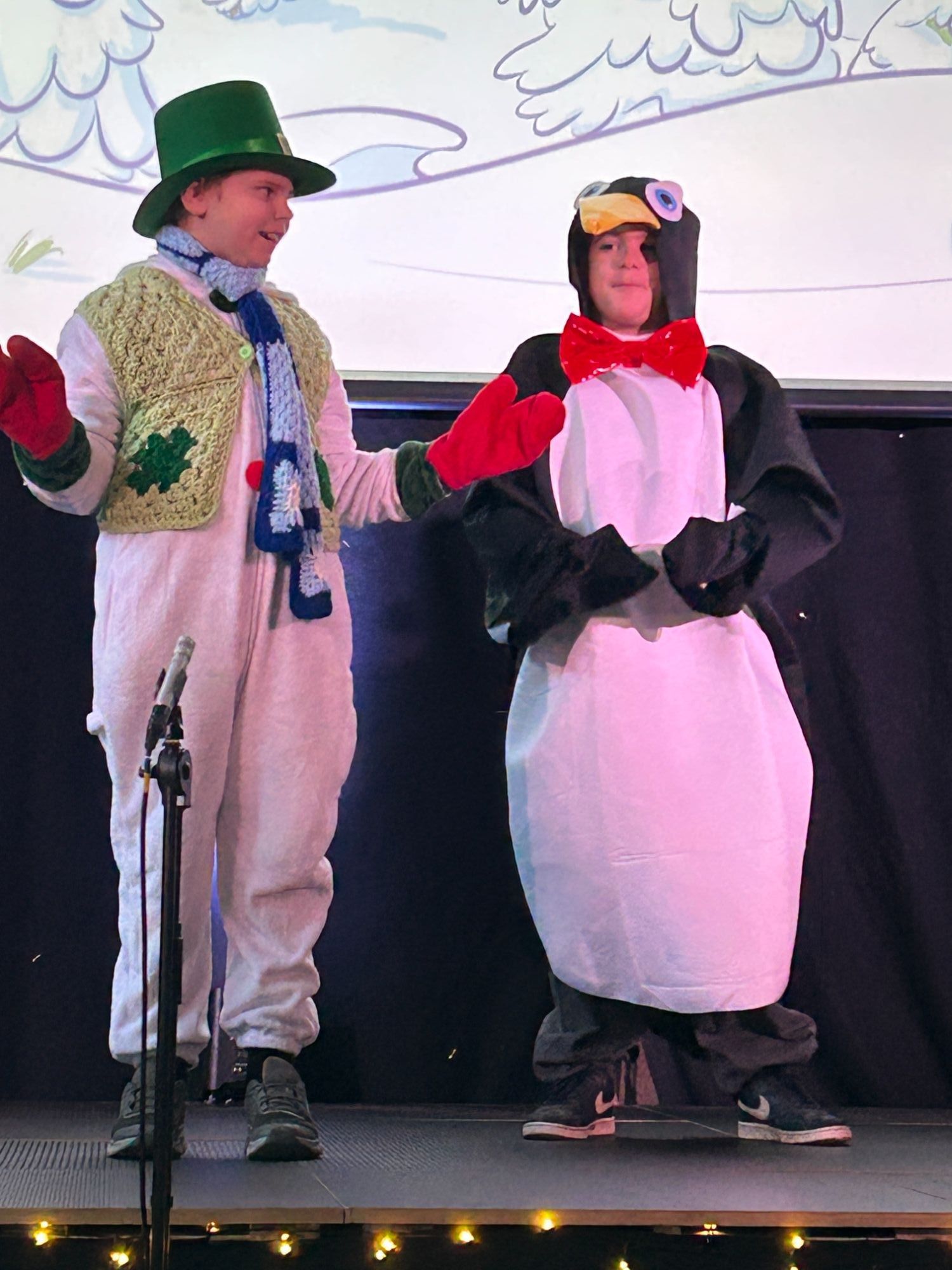 two students on stage one dressed as a snowman and the other a penguin
